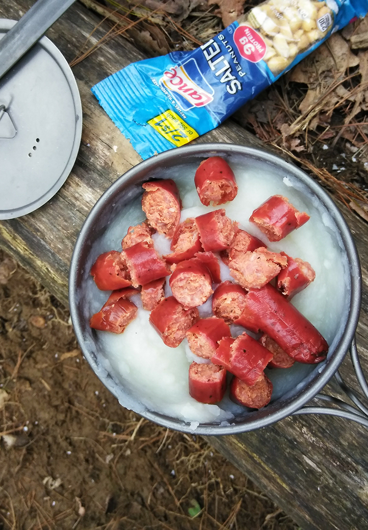 A BearVault being opened by a hiker. The BearVault also keeps your snacks from getting crushed.