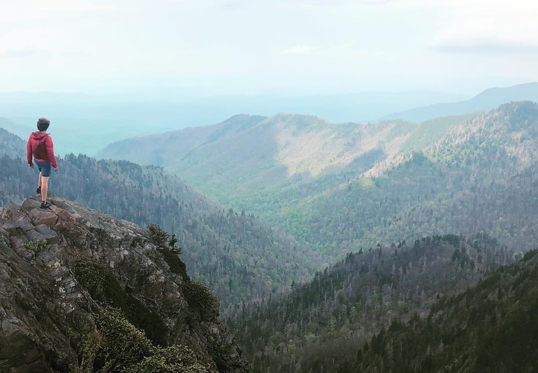 Backpacker reaches for his bear spray from the ULA Deploy Bear Canister Holder on his shoulder strap.
