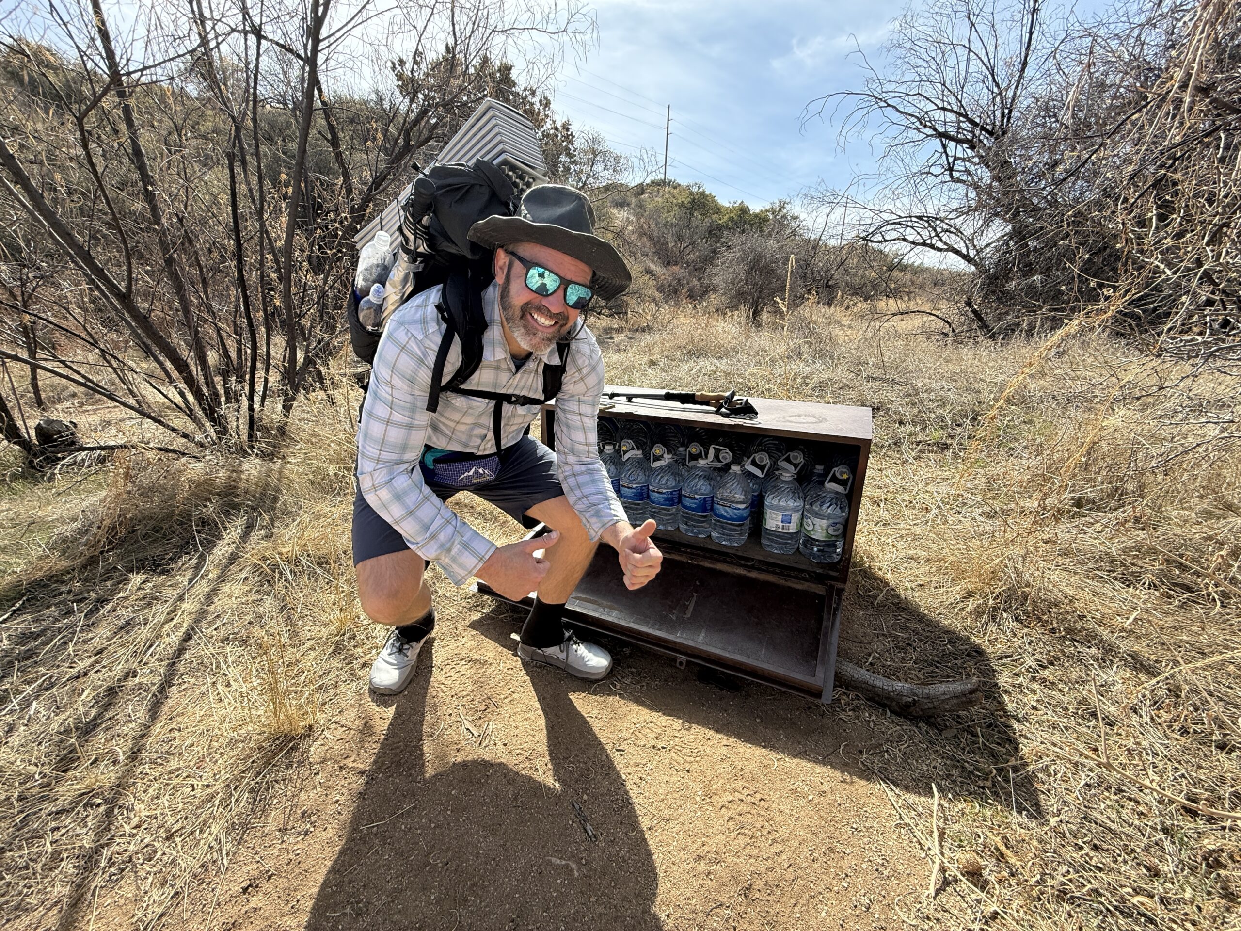A man smiles next to a water cache.