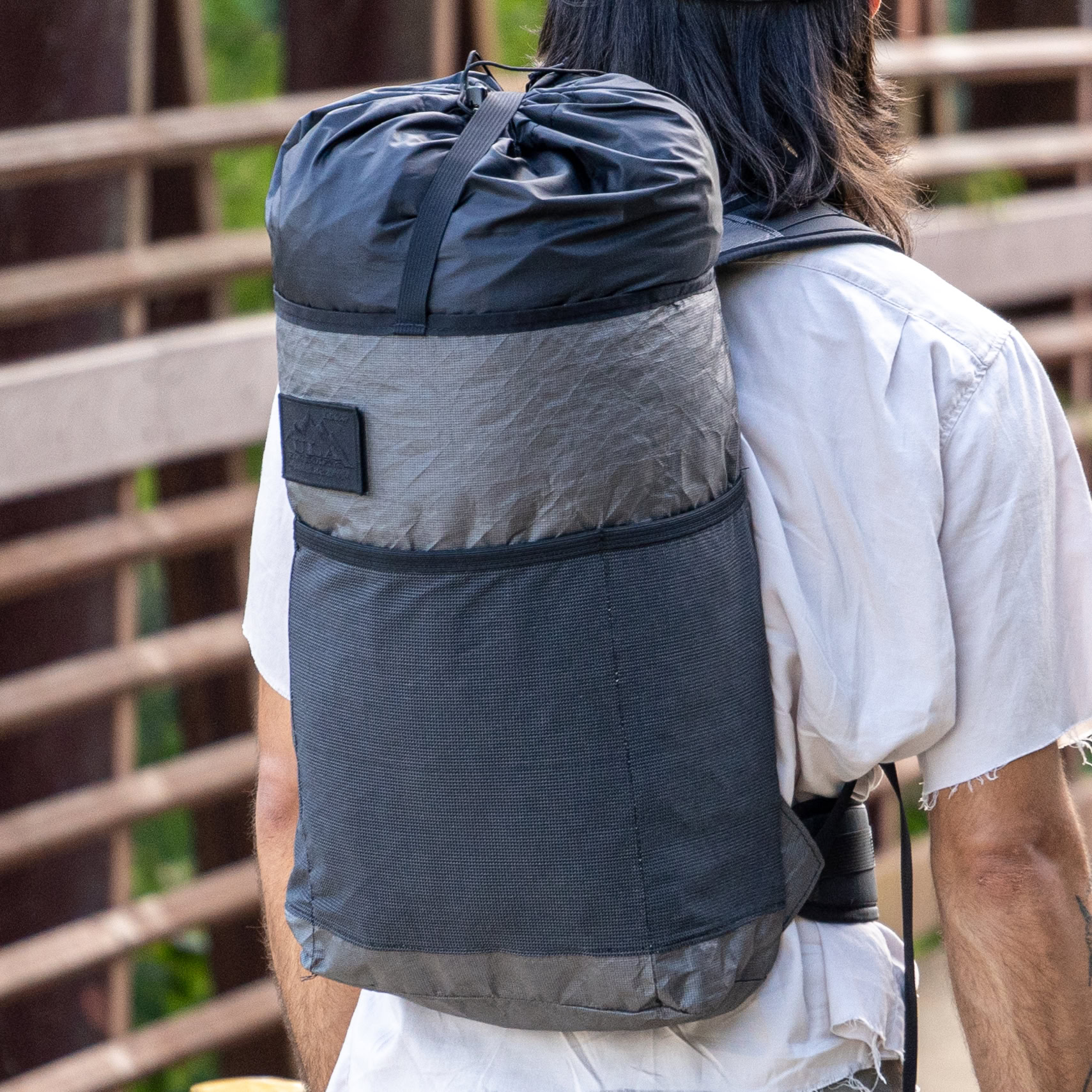 A man models a backpack on a bridge