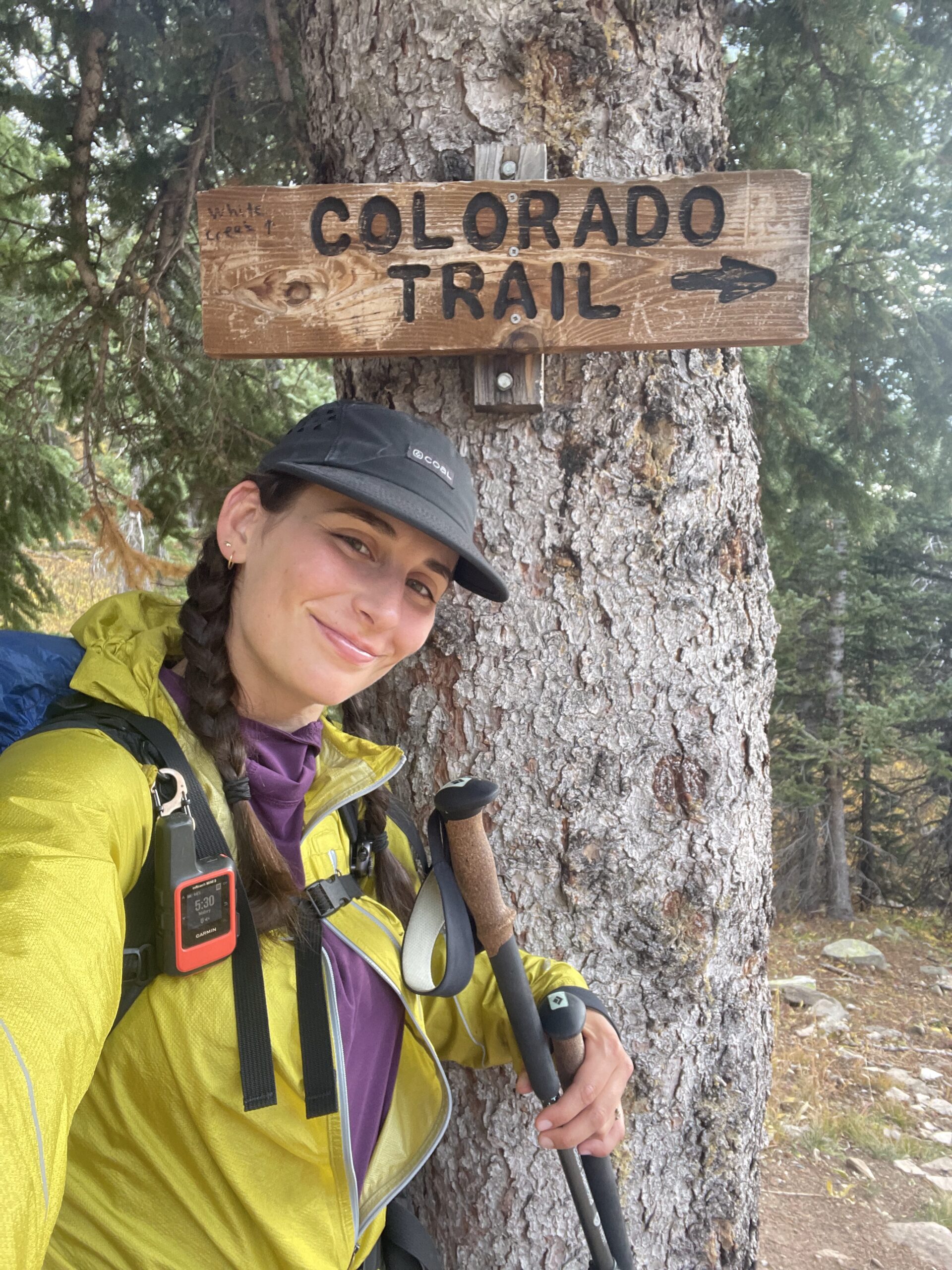 A woman poses next to a wooden sign on the Colorado Trail