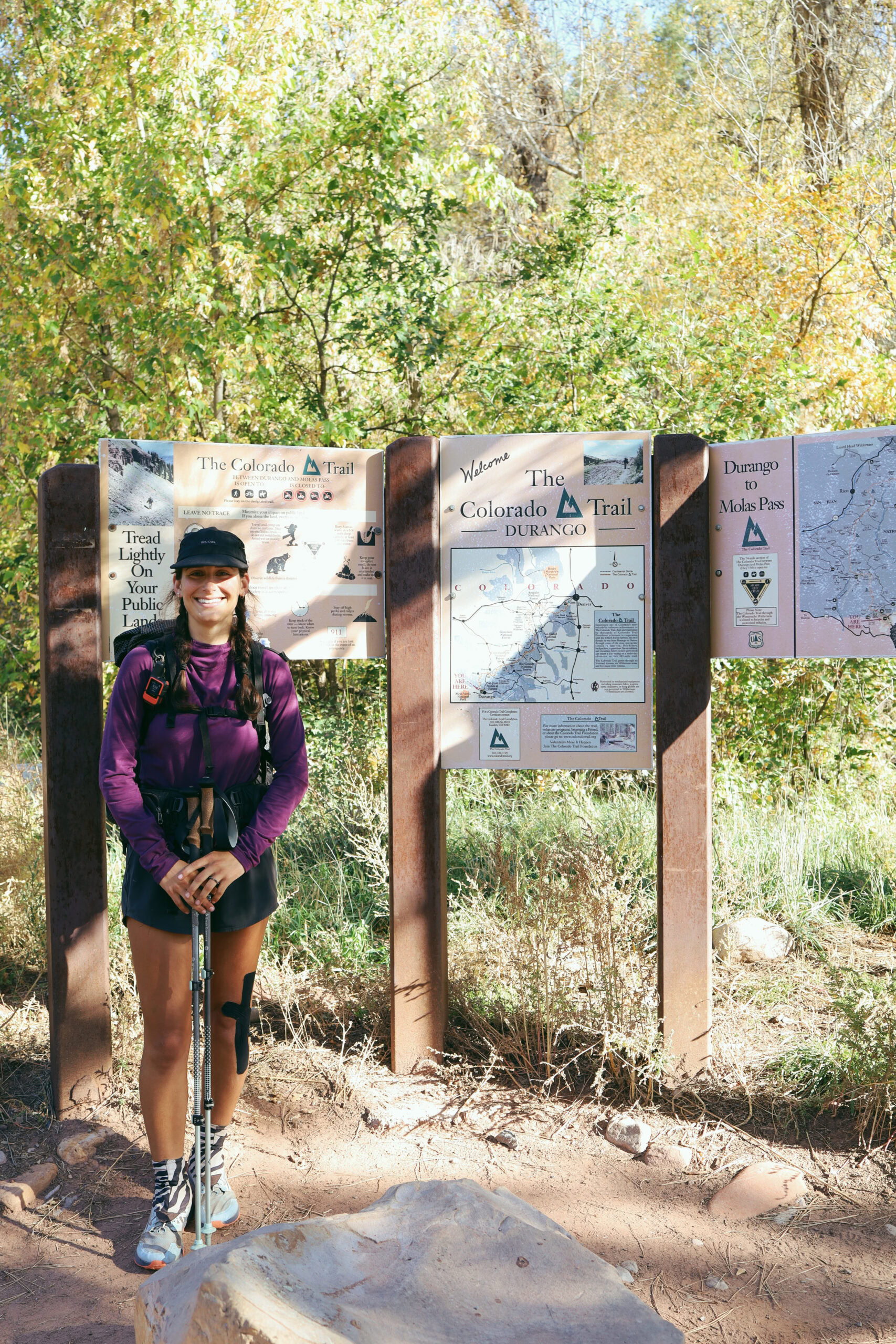 A woman poses next to a trail information board